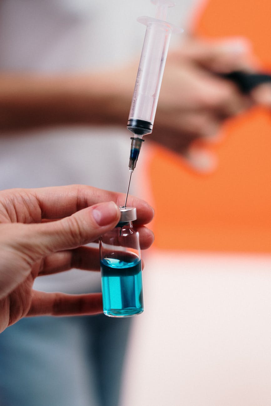 A syringe draws blue liquid from a vial, focusing on precision in healthcare.